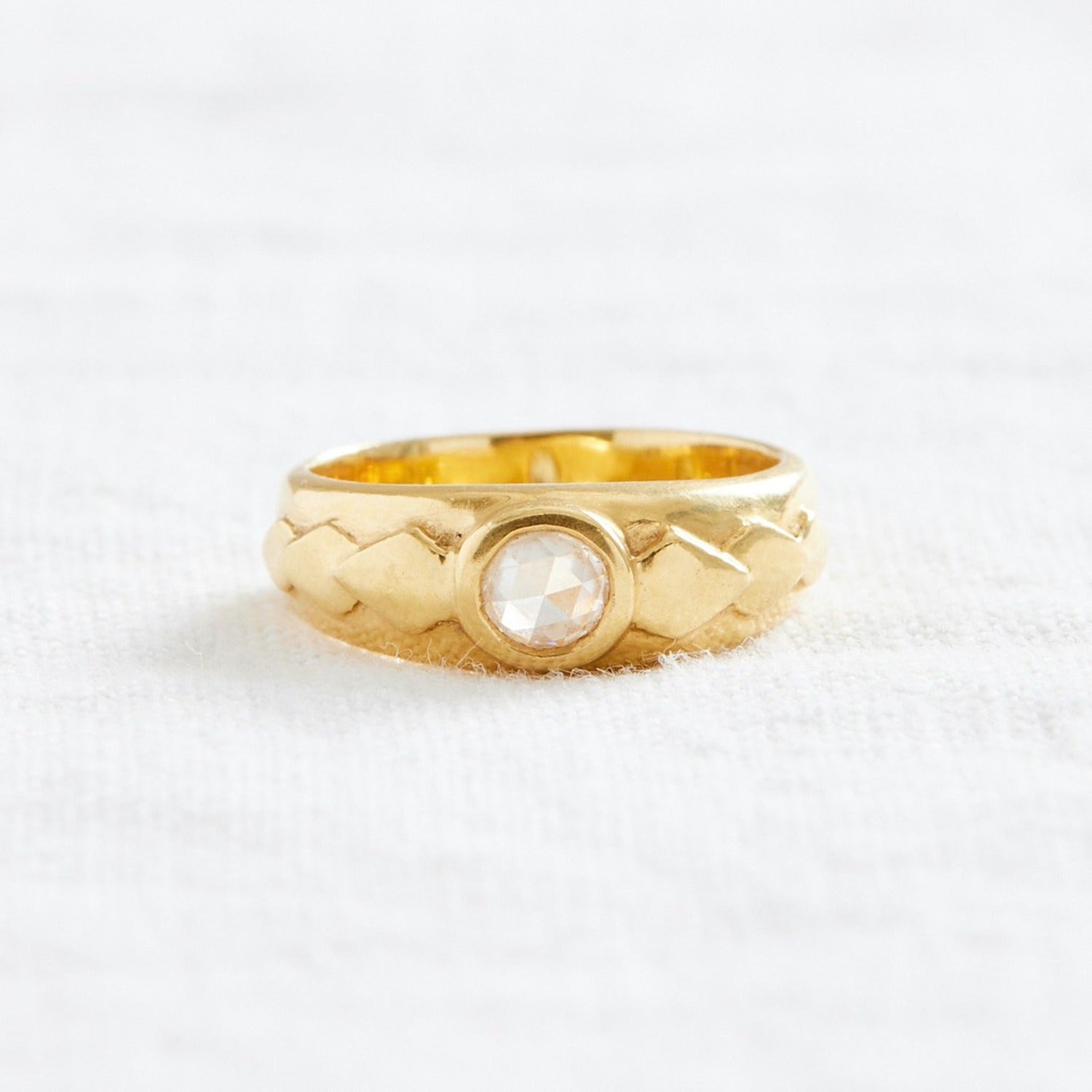gold ring with diamond in the center, and three engraved leaves on either side of the diamond
