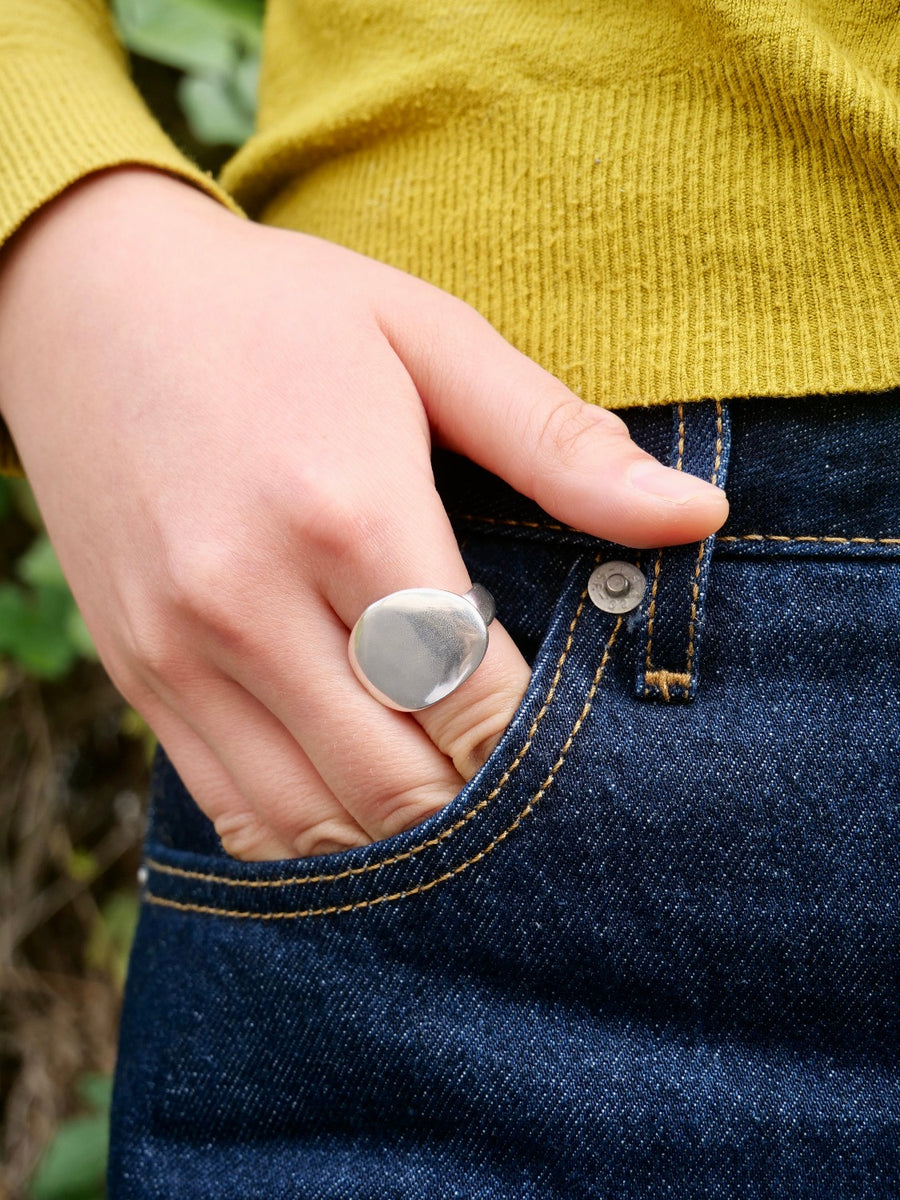 silver stone-shaped signet on hand in jeans pocket