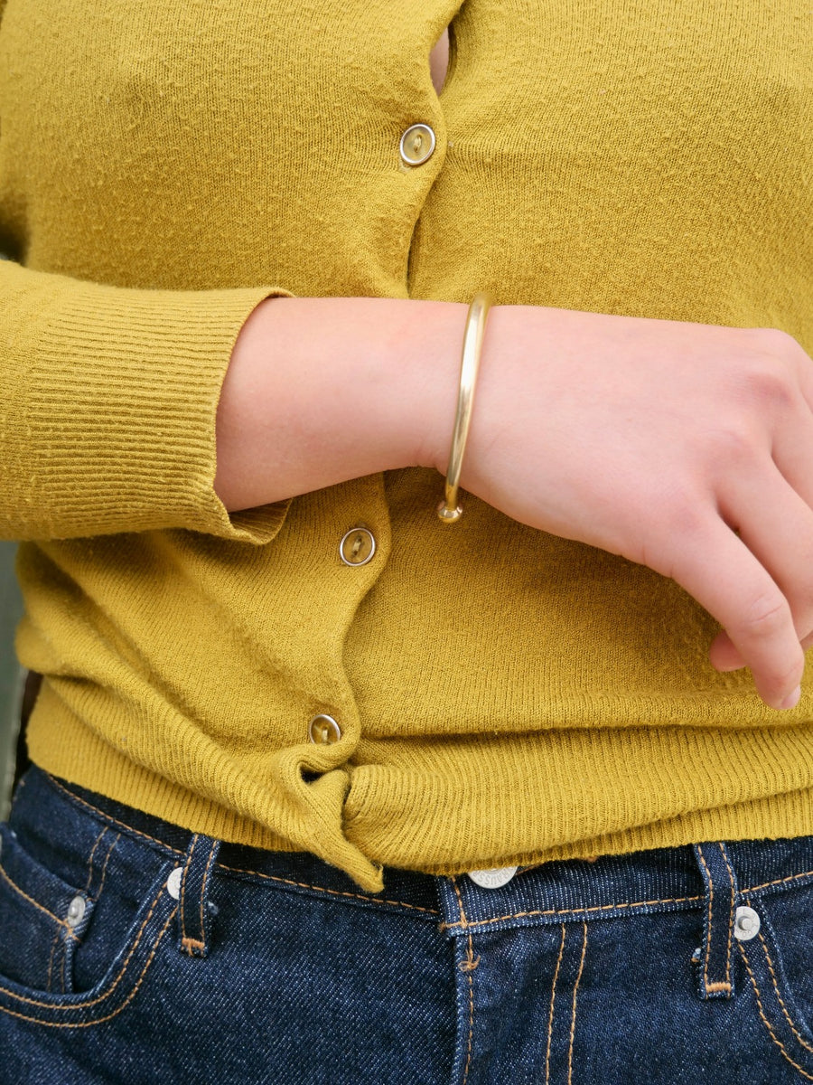 smooth brass thin cuff on model with yellow sweater