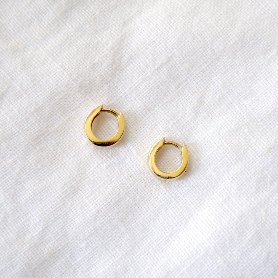 14k yellow gold tapered hinged hoop, 10.25mm in diameter and 4mm wide on white linen