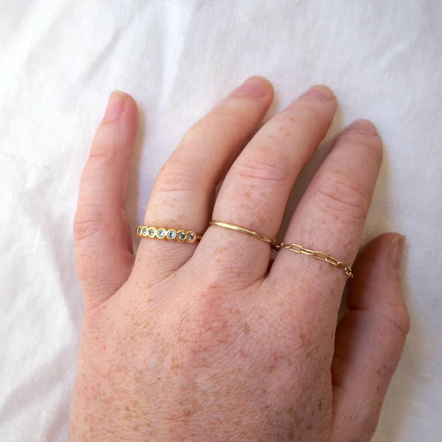 Soft blue Montana Sapphires, bezel set in a simple yellow gold band on model