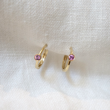 Sweet every day little clicker hoops with a single 2.7mm bezel set pink sapphire in each. Shown on white backdrop.