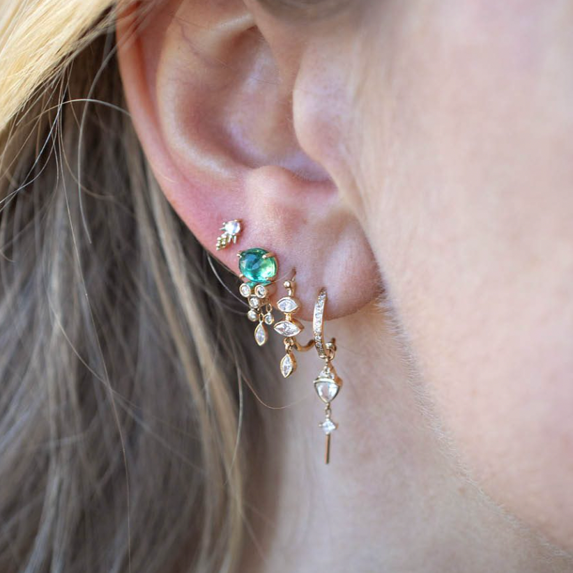 14k light yellow gold single jellyfish earring with one emerald dangling diamonds below it, on model