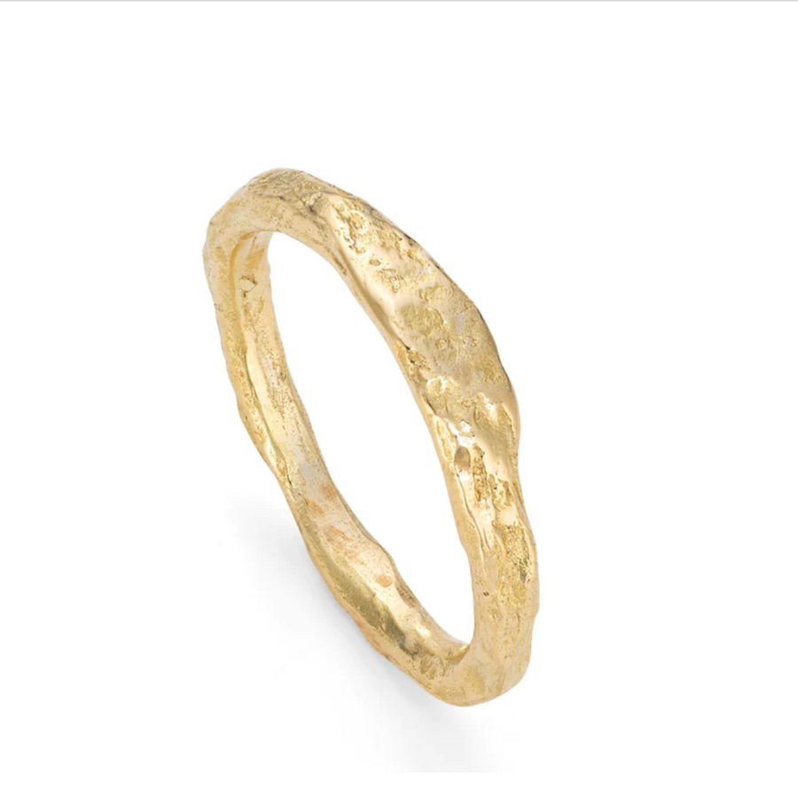 With a flattened top and undulating profile, this stone textured ring has the sea-worn character of nature's texture. An understated, timeless wedding band in 18ct gold.