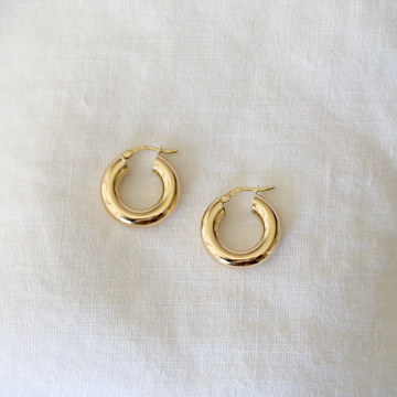 5mm thick, hollow hoops in 14k solid gold with hinge clasp, on white linen background