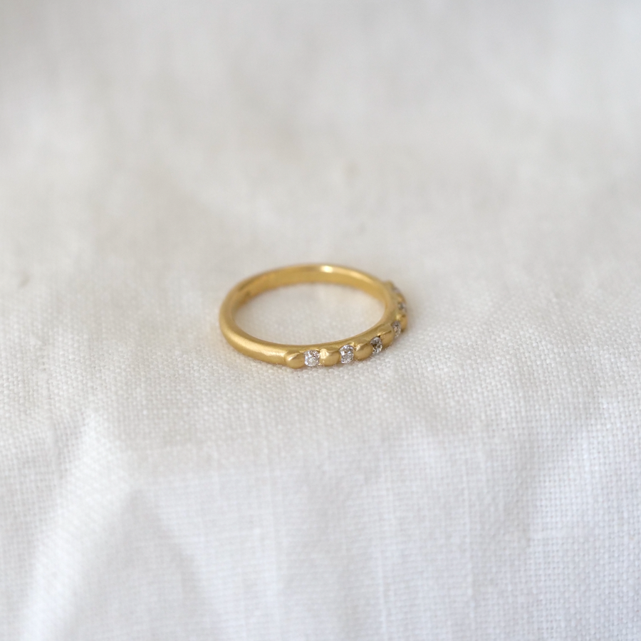 Rounded gold band with carved gold granulation details used to set six white diamonds stones