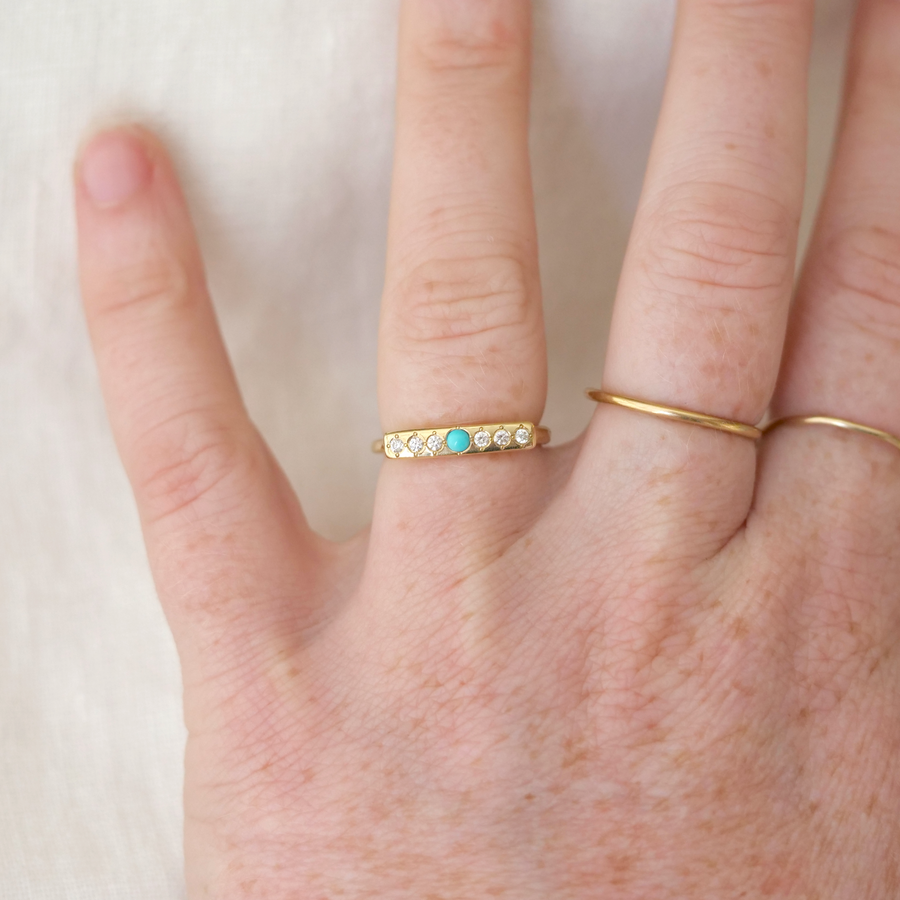 14k ring is set with 1 sleeping beauty turquoise point and 6 white diamonds on a perfectly smooth face on hand model