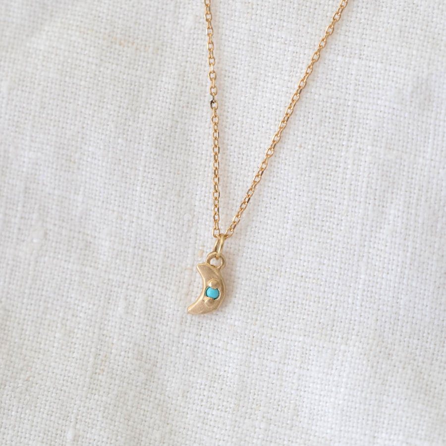 small gold moon with bead set turquoise point in the center, on delicate gold chain