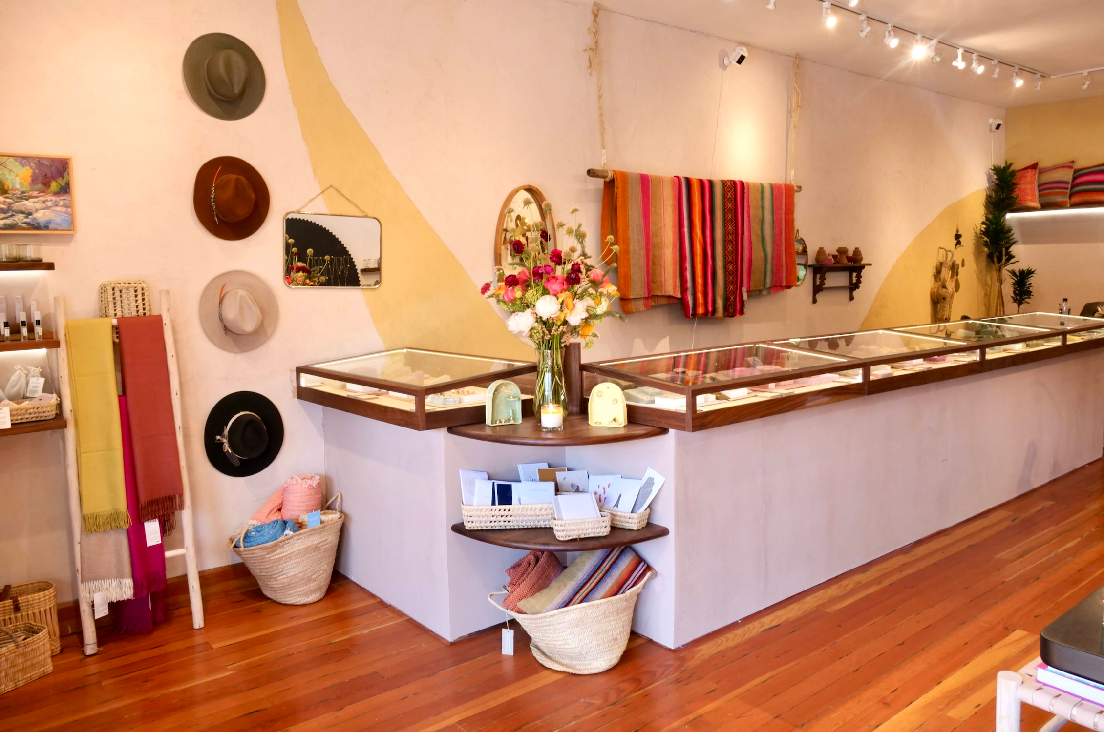 Interior of Berkeley store, looking at the front jewelry cases with flower, hats and blankets hanging on the wall