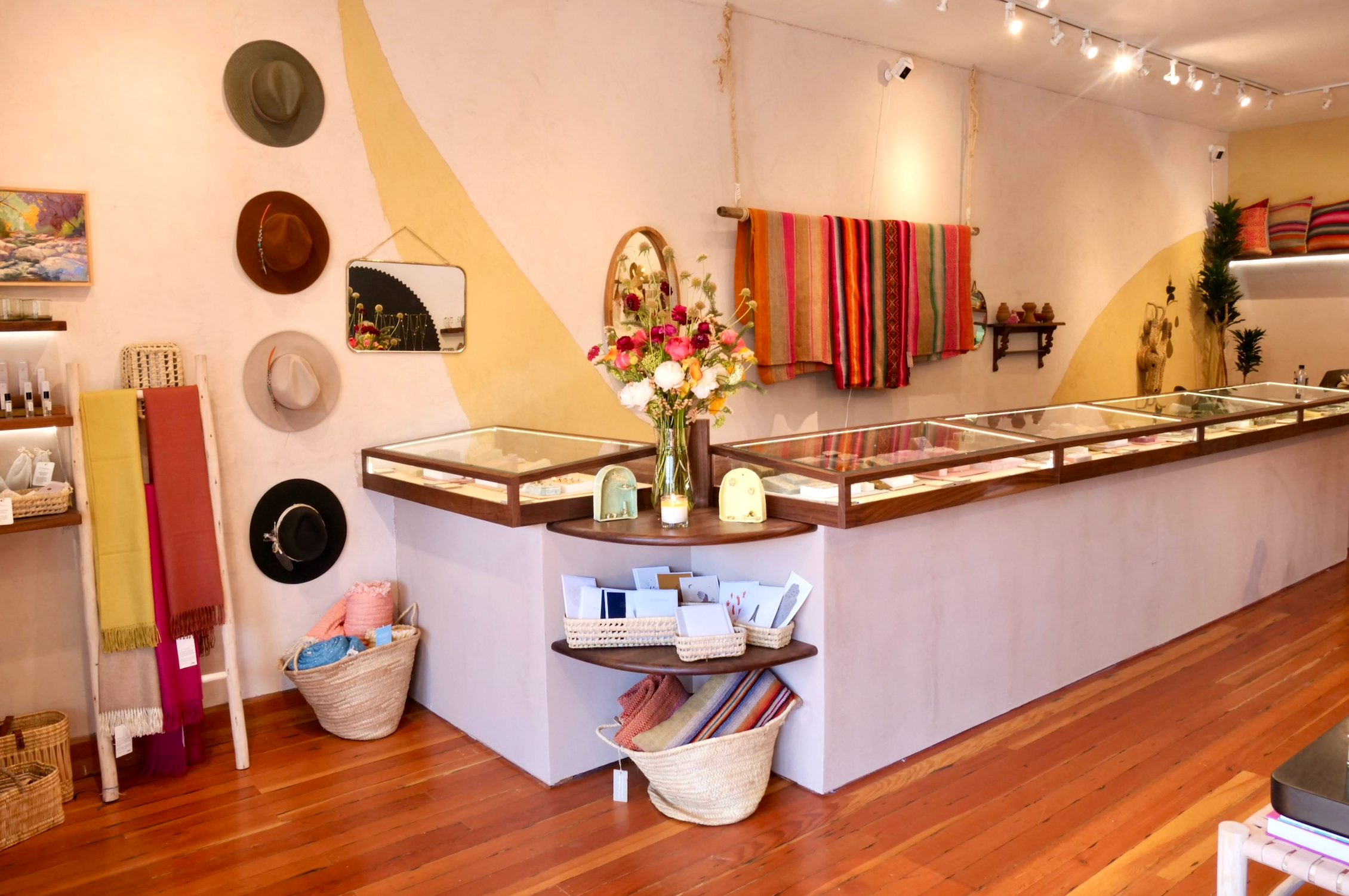 Interior of Berkeley store, looking at the front jewelry cases with flower, hats and blankets hanging on the wall 