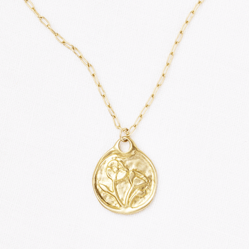A Poppy Medallion necklace by Marisa Mason Jewelry featuring an embossed abstract figure on a delicate chain, displayed against a white background.