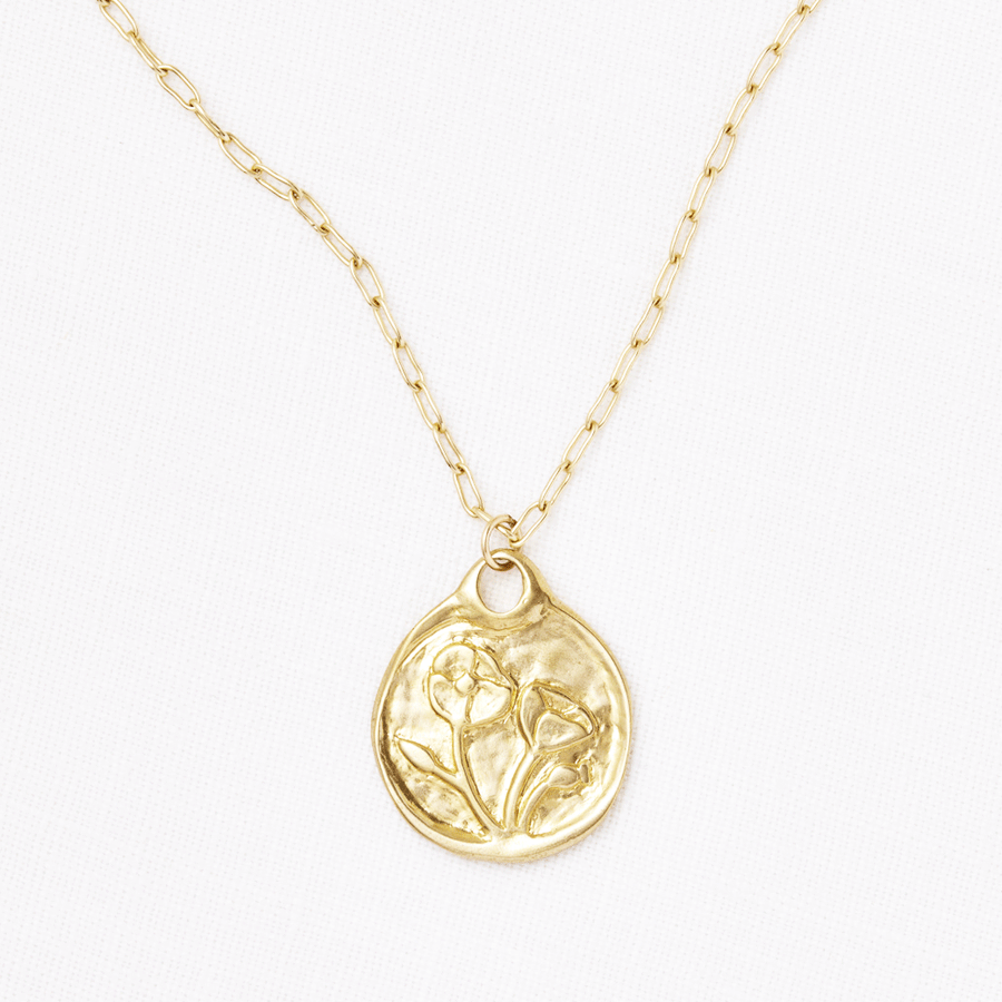 A Poppy Medallion necklace by Marisa Mason Jewelry featuring an embossed abstract figure on a delicate chain, displayed against a white background.