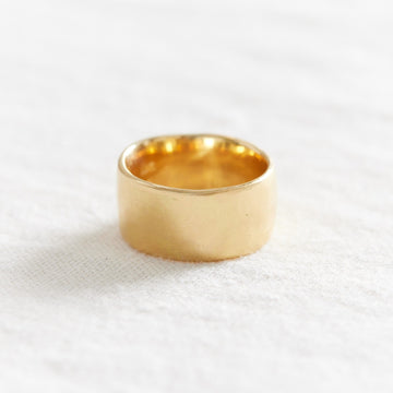 extra wide, solid gold band with slight irregular texture around the edge and surface.