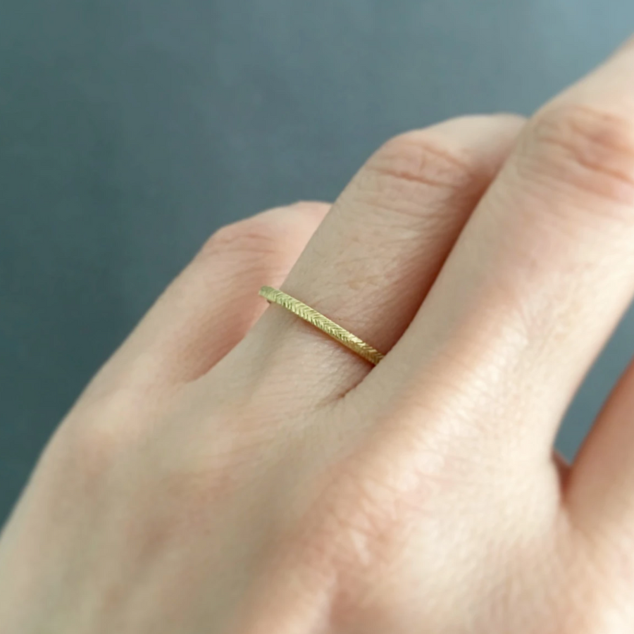 18k gold band with herringbone style etching in the surface on models hand