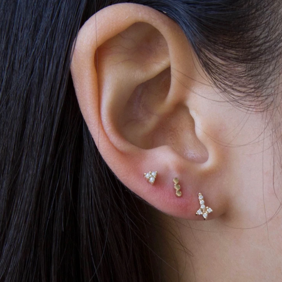 Three round gold dots in a row, creating a bar earrings stud on ear