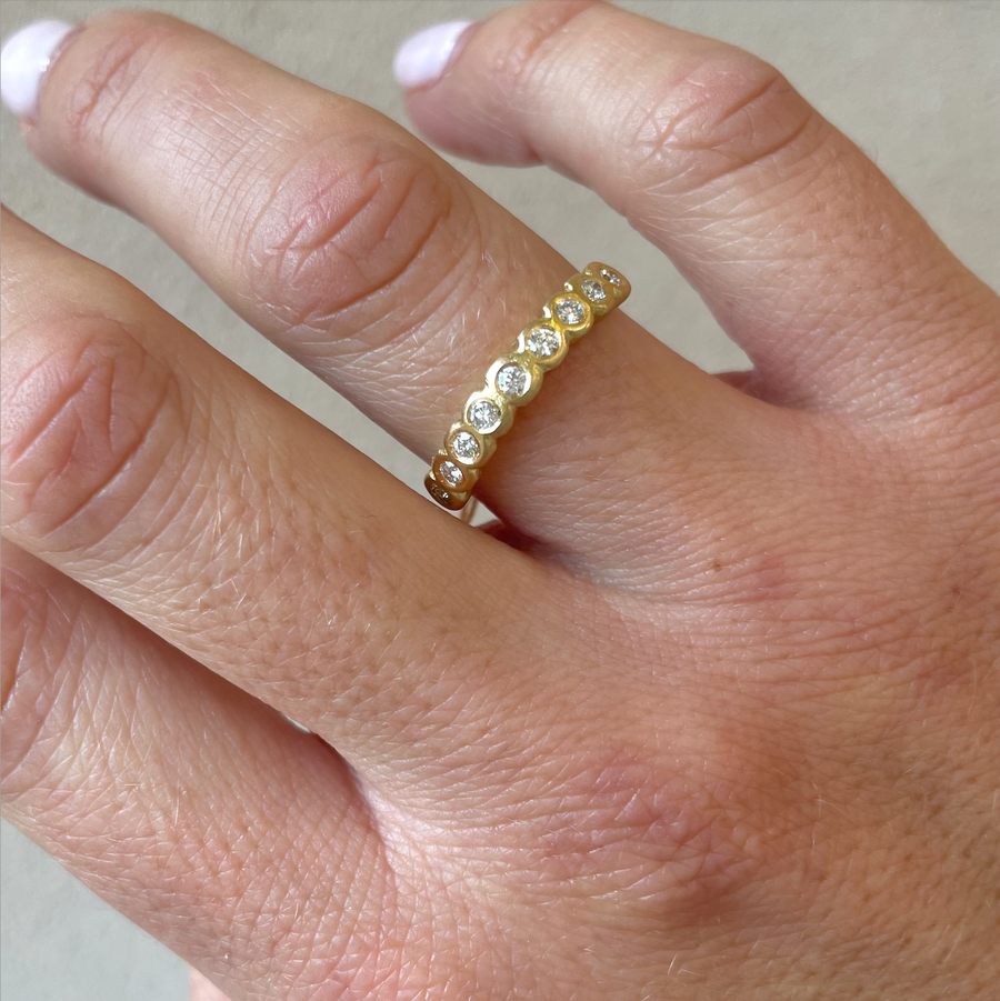 Nine white diamonds bezel set in a simple yellow gold band on models hand -Marisa Mason