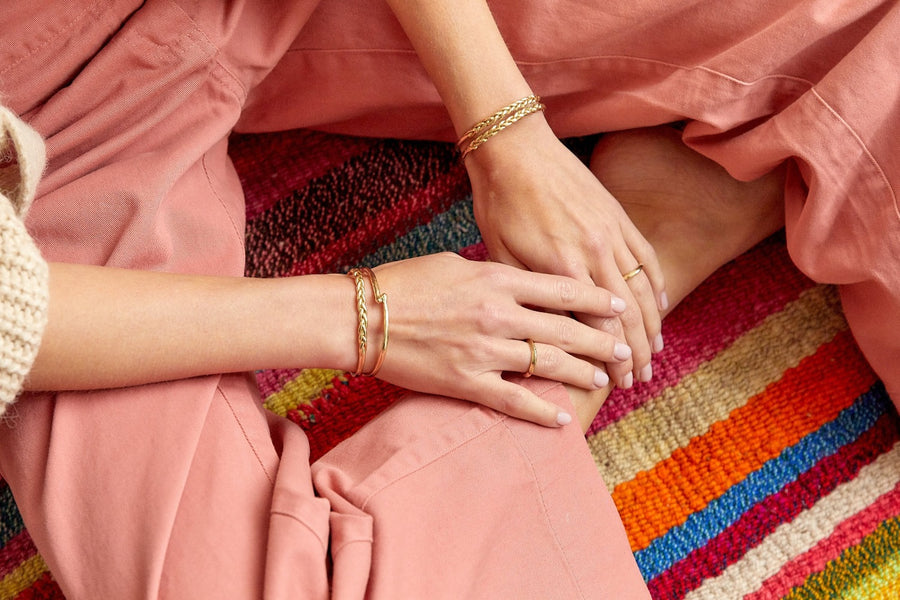 Thin brass bangles on models wrists with braided texture in the center -Marisa Mason Jewelry
