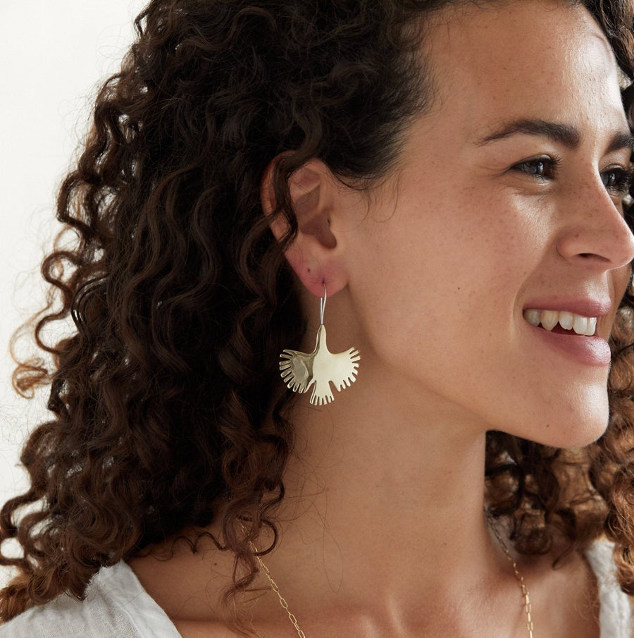 flying bird brass earrings on silver hook ear-wire on model -Marisa Mason Jewelry