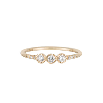 3 white diamonds set in milgrain detailed bezel settings in a row at the center of a thin gold band. To add even more texture, there are three additional smaller diamonds flush set into the band on either side of the large central diamonds.