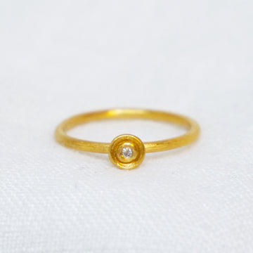 24k gold ring with round disk in the center, with white diamond at the center of that