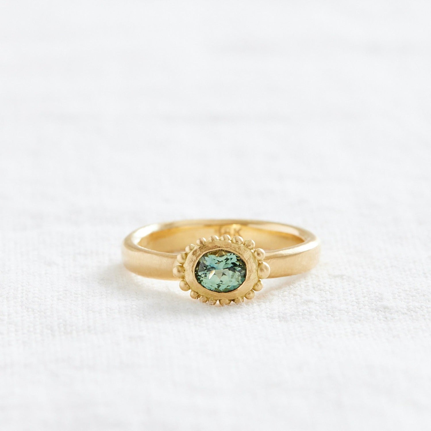 Gold ring with oval teal stone an granulations all around it