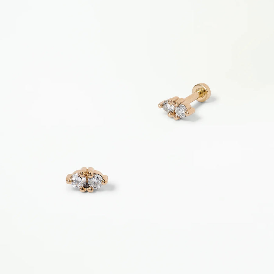 Pair of gold earrings with clear gemstones on a white background