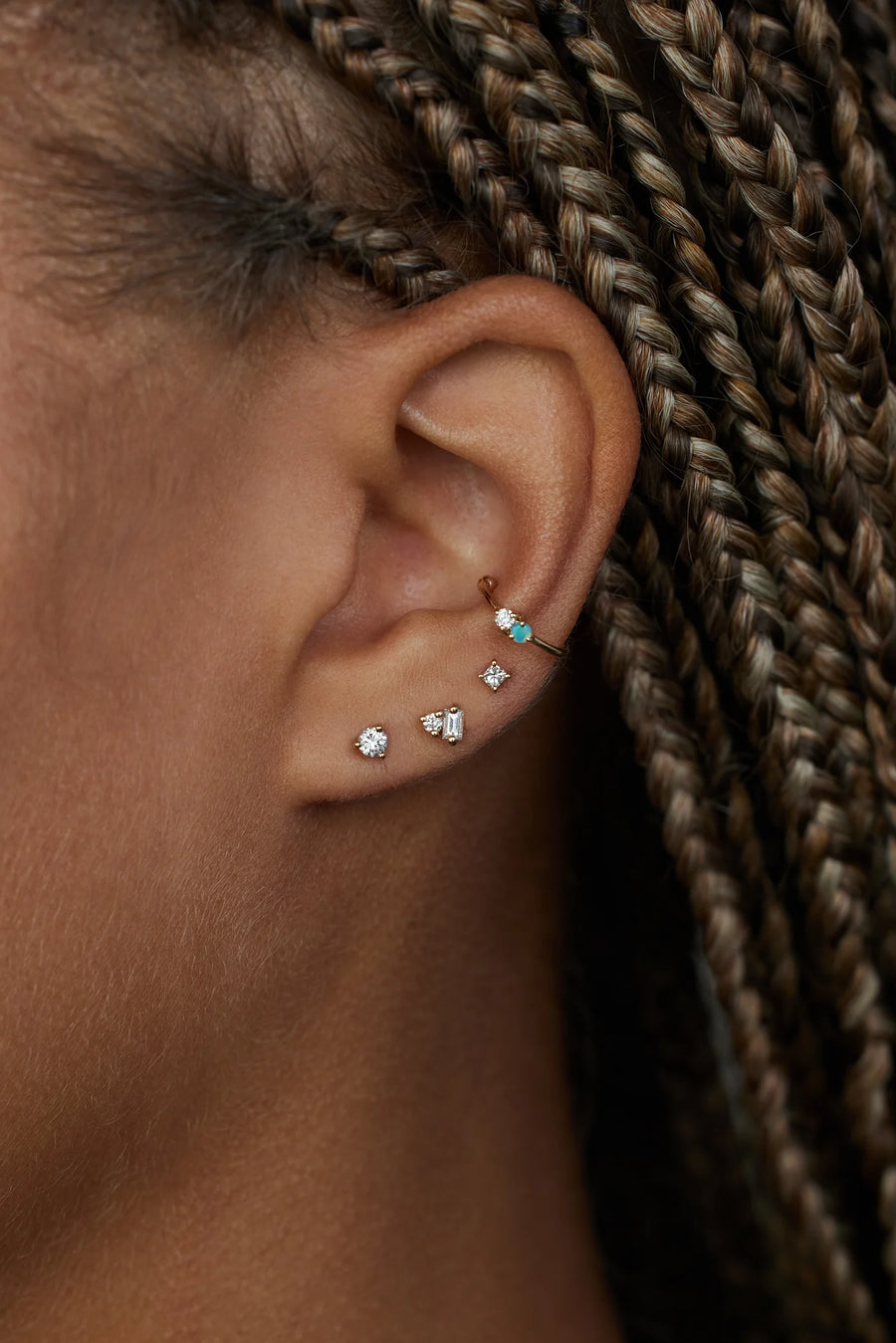 Close-up of an ear with multiple earrings against a blurred background