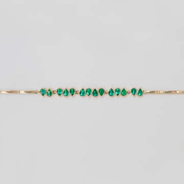 A yellow gold bracelet with articulated teardrop emeralds, featuring an adjustable clasp.