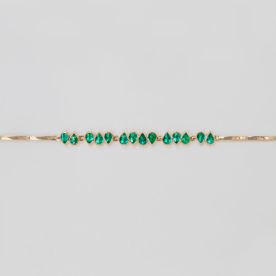 A yellow gold bracelet with articulated teardrop emeralds, featuring an adjustable clasp.