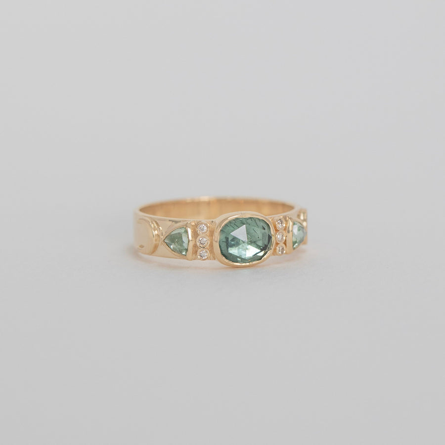Gold ring with a green gemstone on a light gray background