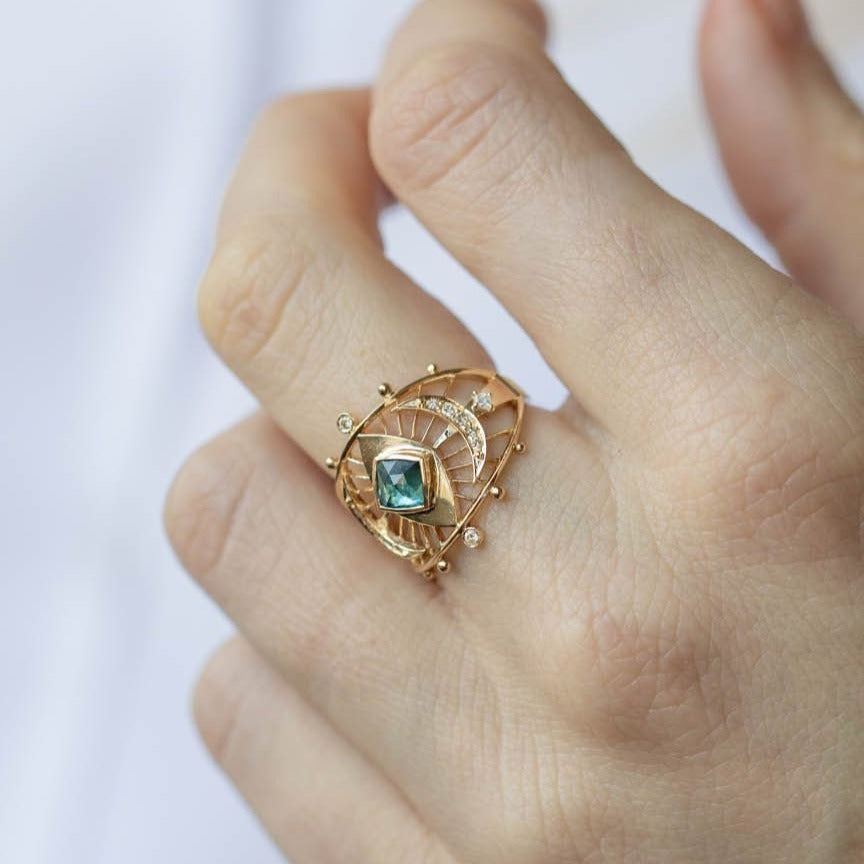 GOLD RING WITH ONE EYE TEAL TOURMALINE, TWO MOON CRESCENTS AND DIAMONDS. THE STONE COMES IN A GRADIENT OF BLUE AND TEAL on hand