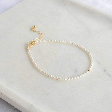 A simple string of tiny fresh water pearls with a delicate 14k gold filled bead at the center