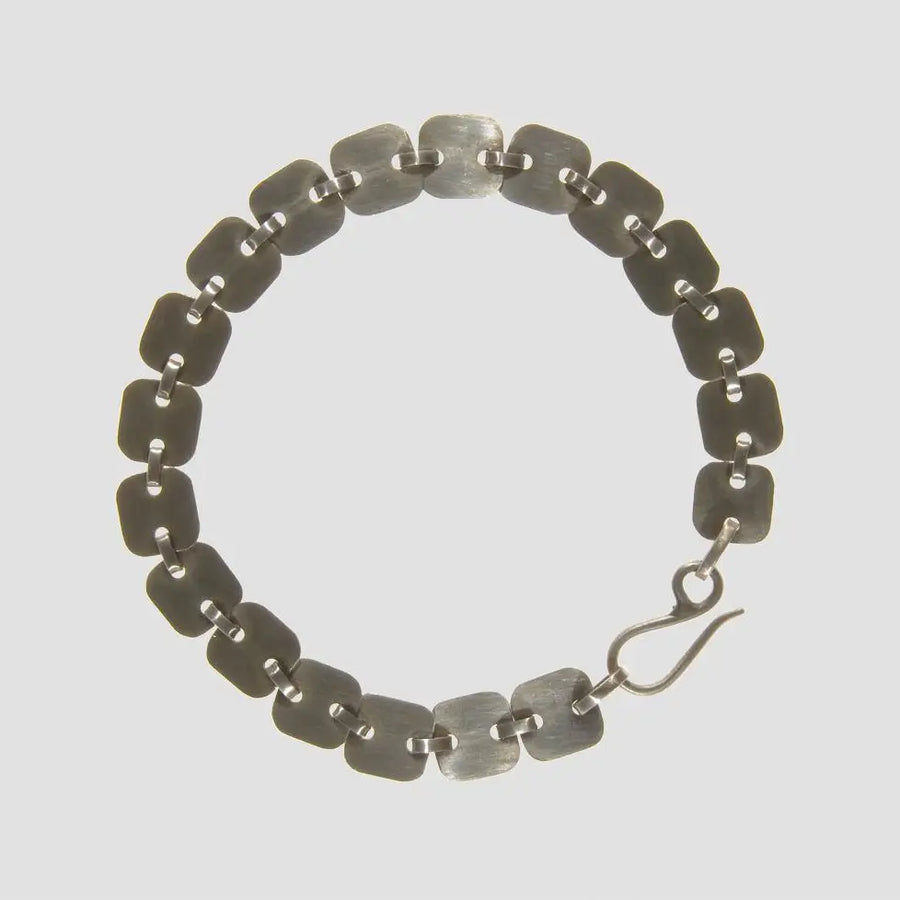 Silver bracelet with a hook clasp on a light gray background