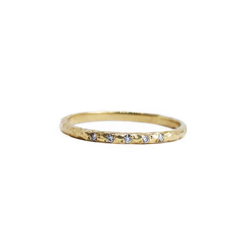 This gorgeous hand-textured ring features a sparkling row of carefully set white diamonds