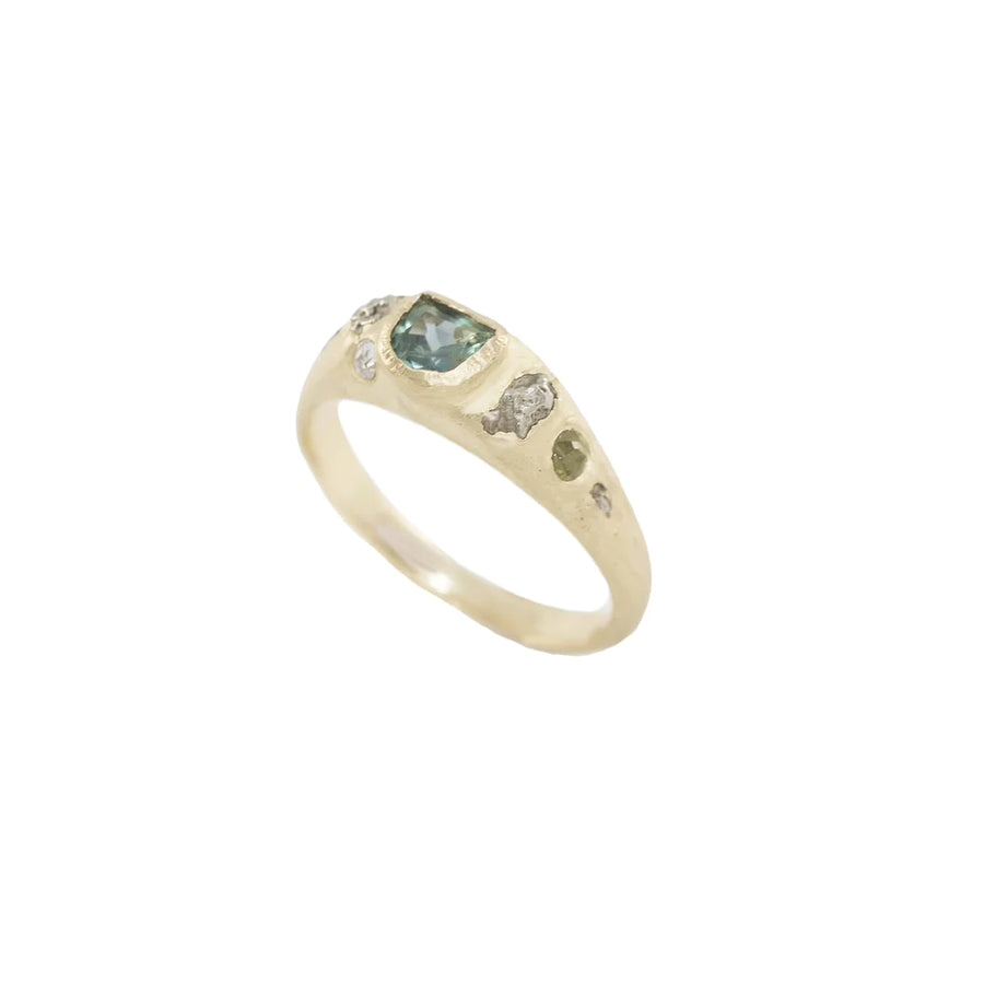 The center stars a .3 karat Montana sapphire accompanied by hand carved white gold rocks. On one side lay a 2mm green diamond, and on the other a 3mm sapphire marquise
