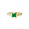 hand carved rock texture on the surface of a 14k yellow gold ring band with a rock setting which holds a beautiful fine emerald