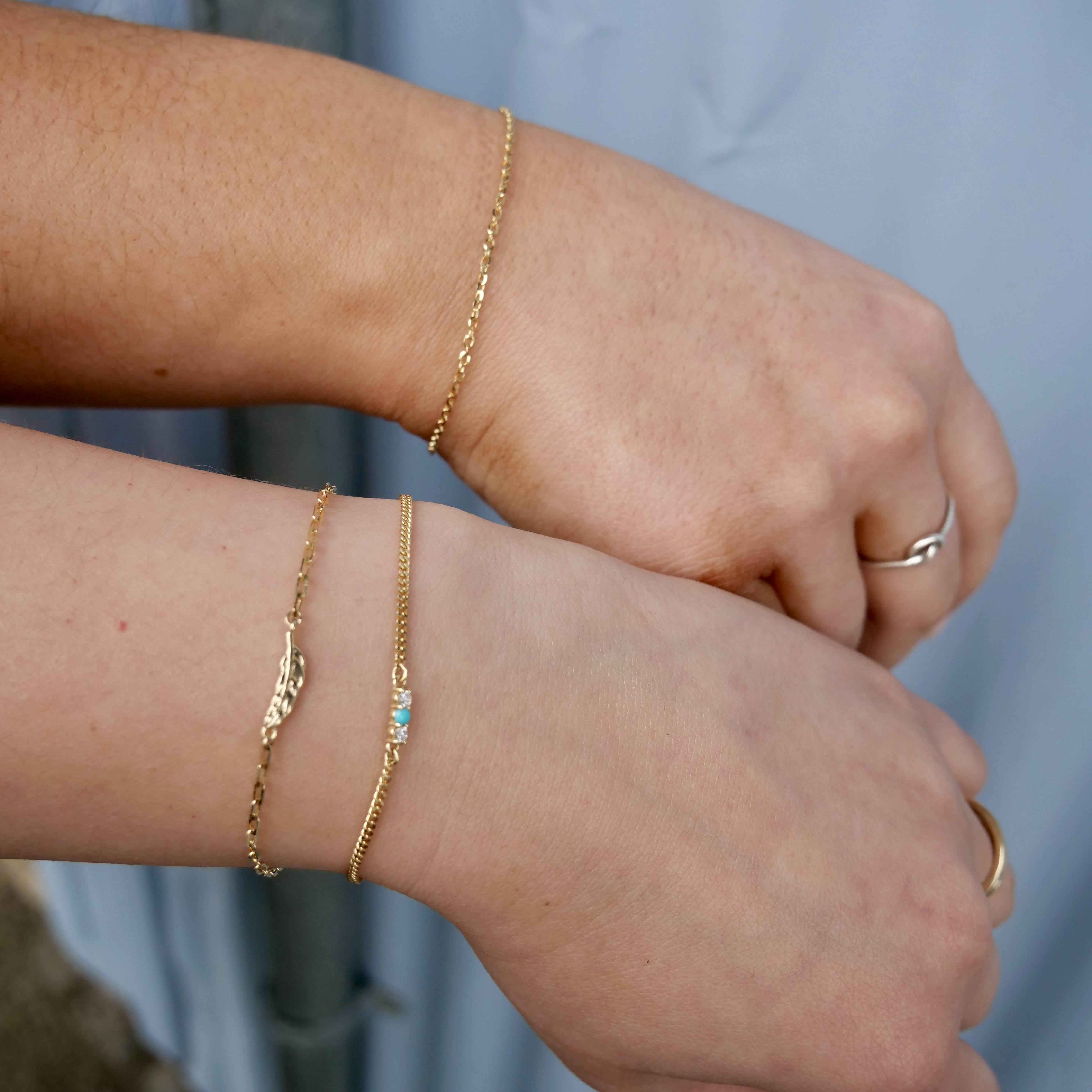 two wrists with gold chain bracelets 