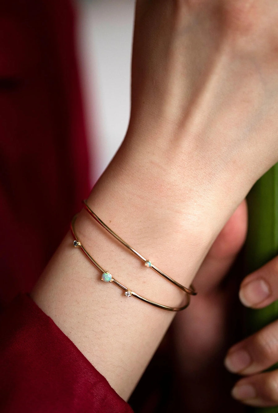 Close-up of a wrist wearing two gold bracelets with small stones.