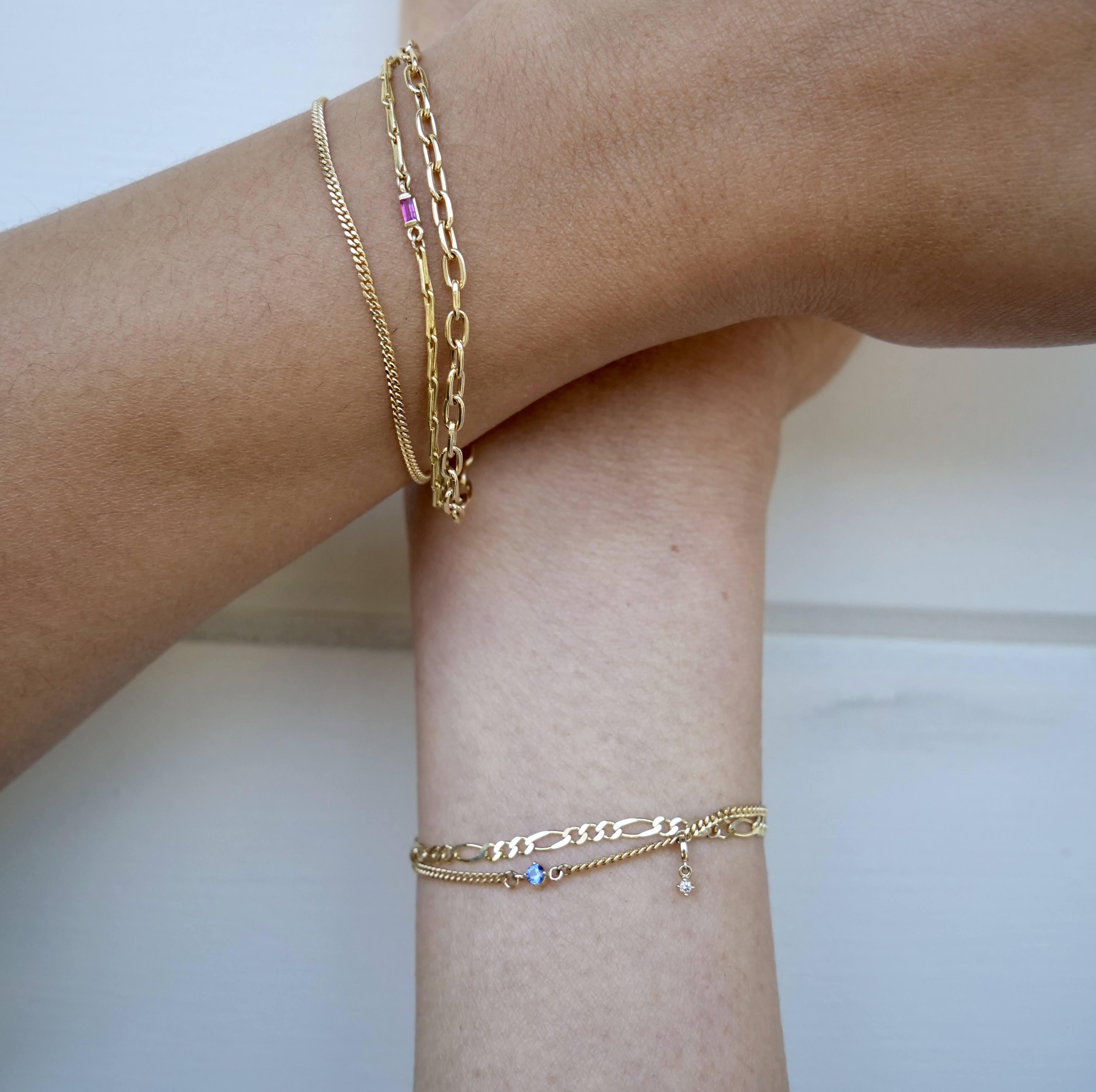 two people with permanent gold chain bracelets with charms