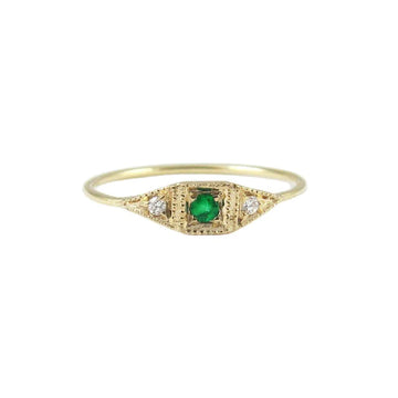 A geometric signet faced ring with a round emerald bead set in the center and two small white diamonds on either side. 