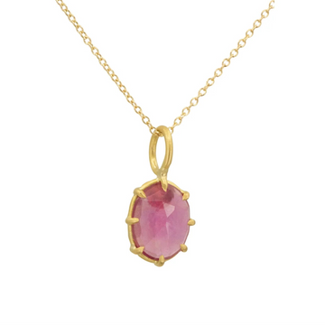 Gold necklace with a pink gemstone pendant on a white background