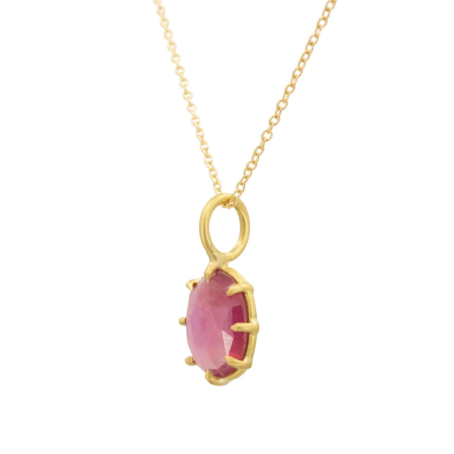 Gold necklace with a pink gemstone pendant on a white background