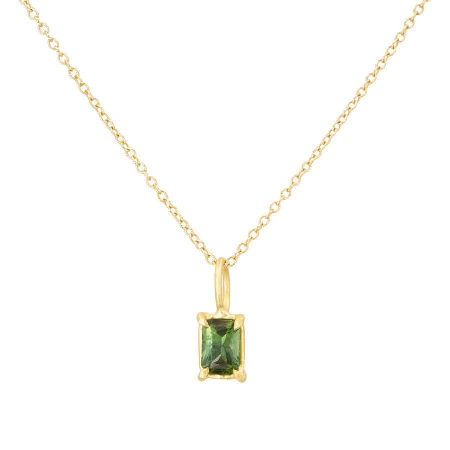 Gold necklace with a green gemstone pendant on a white background