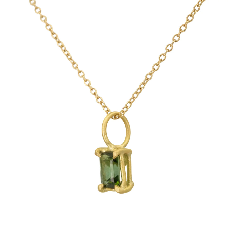 Gold necklace with a green gemstone pendant on a white background