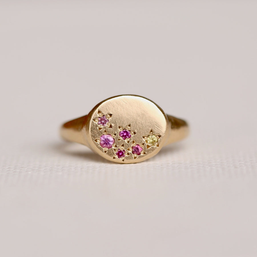 14k oval faced sigent ring with organically laid out beadset sapphires in a mix of pinks and a pop of yellow