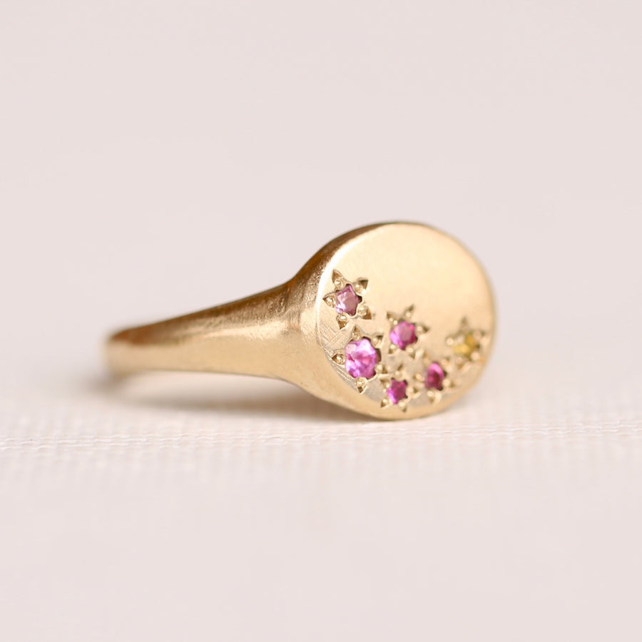 14k oval faced sigent ring with organically laid out beadset sapphires in a mix of pinks and a pop of yellow