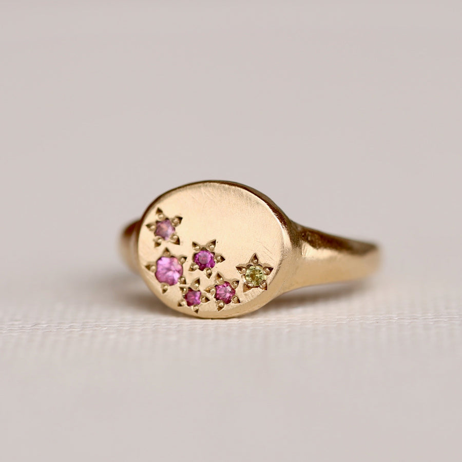 14k oval faced sigent ring with organically laid out beadset sapphires in a mix of pinks and a pop of yellow