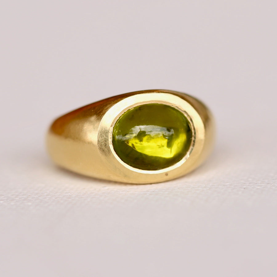 lustrous 18K gold, this chunky power ring features a dramatic peridot cabochon that glimmers with spectacular colors in any lighting