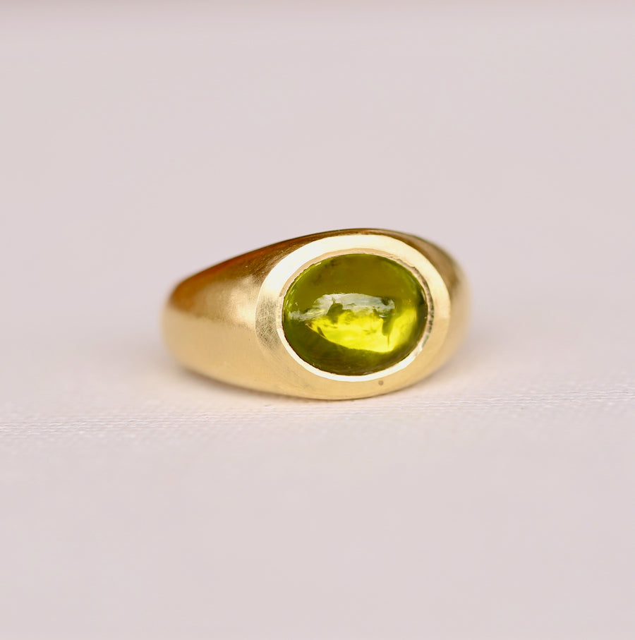 lustrous 18K gold, this chunky power ring features a dramatic peridot cabochon that glimmers with spectacular colors in any lighting