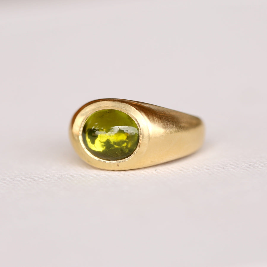 lustrous 18K gold, this chunky power ring features a dramatic peridot cabochon that glimmers with spectacular colors in any lighting